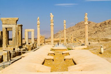 Persepolis UNESCO Dünya Mirasları Alanında İran 'ın Şiraz şehrinde bulutlu mavi gökyüzüne karşı levrek kabartması ile merdivenlerin arkasındaki Apadana ve Tachara Sarayı harabeleri. Orta Doğu, Asya