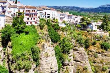 Güneşli bir günde İspanya 'nın güneyindeki Andalucian kasabasında kayalıklardan sarkan evler. Ronda, beyaz şehir rotasında popüler bir turizm merkezidir ve çoğu turist tarafından sık sık ziyaret edilir.