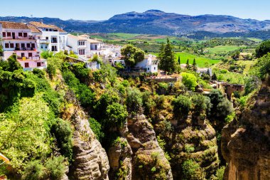 Güneşli bir günde İspanya 'nın güneyindeki Andalucian kasabasında kayalıklardan sarkan evler. Ronda, beyaz şehir rotasında popüler bir turizm merkezidir ve çoğu turist tarafından sık sık ziyaret edilir.