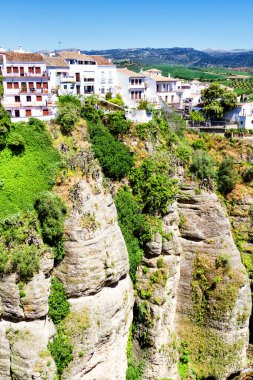 Güneşli bir günde İspanya 'nın güneyindeki Andalucian kasabasında kayalıklardan sarkan evler. Ronda, beyaz şehir rotasında popüler bir turizm merkezidir ve çoğu turist tarafından sık sık ziyaret edilir.