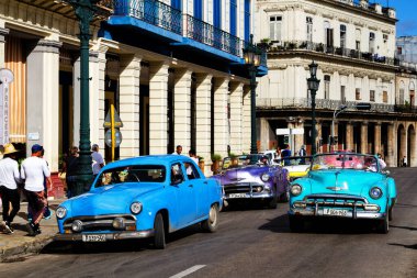 HAVANA, CUBA - 14 Kasım 2017: İnsanlar, eski arabalar ve renkli binaların olduğu tipik sokak sahnesi. 2 milyondan fazla nüfusuyla Havana, Küba 'nın başkenti ve Karayipler' in en büyük şehridir.