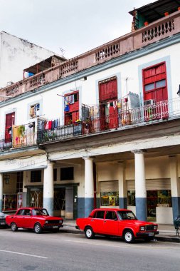 HAVANA, CUBA - 14 Kasım 2017: İnsanlar, eski arabalar ve renkli binaların olduğu tipik sokak sahnesi. 2 milyondan fazla nüfusuyla Havana, Küba 'nın başkenti ve Karayipler' in en büyük şehridir.