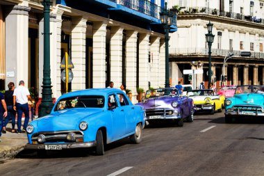 HAVANA, CUBA - 14 Kasım 2017: İnsanlar, eski arabalar ve renkli binaların olduğu tipik sokak sahnesi. 2 milyondan fazla nüfusuyla Havana, Küba 'nın başkenti ve Karayipler' in en büyük şehridir.