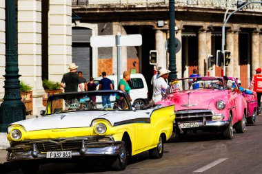 HAVANA, CUBA - 14 Kasım 2017: İnsanlar, eski arabalar ve renkli binaların olduğu tipik sokak sahnesi. 2 milyondan fazla nüfusuyla Havana, Küba 'nın başkenti ve Karayipler' in en büyük şehridir.
