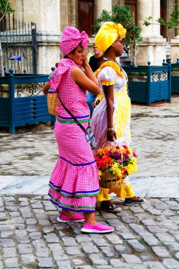 HAVANA, CUBA - 17 NOV 2017: Küba 'nın Havana kentinde büyük bir Küba purosu içerken geleneksel ve tipik kıyafetler giymiş Kübalı kadınlar fotoğraf için poz veriyorlar.
