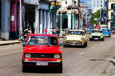 HAVANA, CUBA - 14 Kasım 2017: İnsanlar, eski arabalar ve renkli binaların olduğu tipik sokak sahnesi. 2 milyondan fazla nüfusuyla Havana, Küba 'nın başkenti ve Karayipler' in en büyük şehridir.