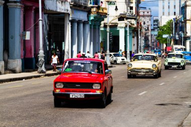 HAVANA, CUBA - 14 Kasım 2017: İnsanlar, eski arabalar ve renkli binaların olduğu tipik sokak sahnesi. 2 milyondan fazla nüfusuyla Havana, Küba 'nın başkenti ve Karayipler' in en büyük şehridir.