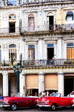 HAVANA, CUBA - 14 Kasım 2017: İnsanlar, eski arabalar ve renkli binaların olduğu tipik sokak sahnesi. 2 milyondan fazla nüfusuyla Havana, Küba 'nın başkenti ve Karayipler' in en büyük şehridir.
