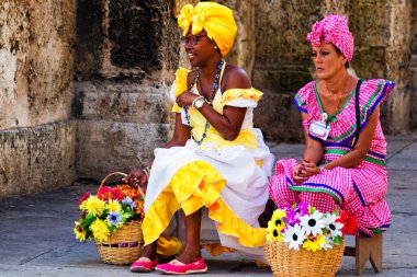 HAVANA, CUBA - NOV 17, 2017: Cuban ladies dressed in traditional and typical clothes posing for photos while smoking a huge cuban cigars in Havana, Cuba. clipart