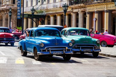 HAVANA, CUBA - 14 Kasım 2017: İnsanlar, eski arabalar ve renkli binaların olduğu tipik sokak sahnesi. 2 milyondan fazla nüfusuyla Havana, Küba 'nın başkenti ve Karayipler' in en büyük şehridir.