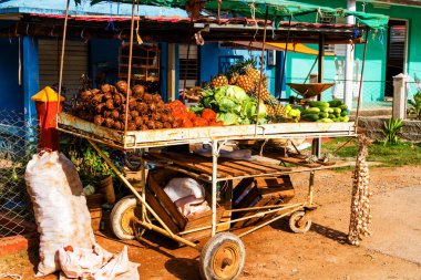 Küba 'nın Vinales kentindeki bir binanın önünde market tezgahı görevi gören eski, basit bir tramvayda satılık meyve ve sebzeler. Özel teşebbüs Küba 'da yeni..
