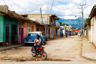 TRINIDAD, CUBA - 22 Kasım 2017: İnsanlar, eski arabalar ve renkli binaların olduğu tipik sokak sahnesi. Trinidad popüler bir turizm merkezidir ve mimarisi ve klasik tarzıyla ünlüdür.