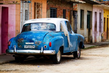TRINIDAD, CUBA - 22 Kasım 2017: İnsanlar, eski arabalar ve renkli binaların olduğu tipik sokak sahnesi. Trinidad popüler bir turizm merkezidir ve mimarisi ve klasik tarzıyla ünlüdür.
