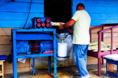 VALLE DE INJENIOS, CUBA - 25 Kasım 2017: Satıcı Trinidad, Küba yakınlarındaki Valle de Ingenios 'ta bir yol kenarındaki bir büfede taze şeker konservesi suyu hazırlıyor