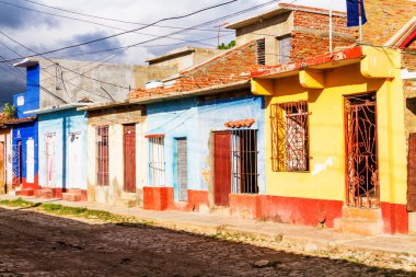 TRINIDAD, CUBA - 21 Kasım 2017: Renkli (kırmızı, sarı, yeşil, mavi) Trinidad caddesi manzaralı evler, kaldırımlı yollar ve pencerelerde parmaklıklar. Trinidad, UNESCO tarafından listelenmiş ve popüler bir şehir..