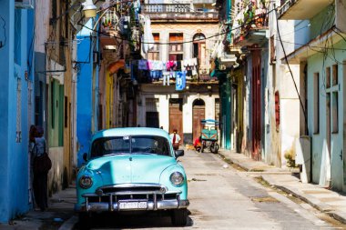 HAVANA, CUBA - 14 Kasım 2017: İnsanlar, eski arabalar ve renkli binaların olduğu tipik sokak sahnesi. 2 milyondan fazla nüfusuyla Havana, Küba 'nın başkenti ve Karayipler' in en büyük şehridir.