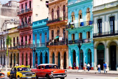 HAVANA, CUBA - 14 Kasım 2017: İnsanlar, eski arabalar ve renkli binaların olduğu tipik sokak sahnesi. 2 milyondan fazla nüfusuyla Havana, Küba 'nın başkenti ve Karayipler' in en büyük şehridir.