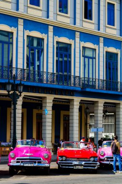 HAVANA, CUBA - 14 Kasım 2017: İnsanlar, eski arabalar ve renkli binaların olduğu tipik sokak sahnesi. 2 milyondan fazla nüfusuyla Havana, Küba 'nın başkenti ve Karayipler' in en büyük şehridir.