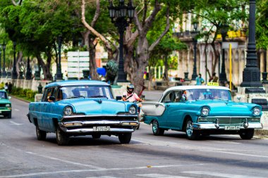HAVANA, CUBA - 14 Kasım 2017: İnsanlar, eski arabalar ve renkli binaların olduğu tipik sokak sahnesi. 2 milyondan fazla nüfusuyla Havana, Küba 'nın başkenti ve Karayipler' in en büyük şehridir.