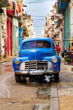 HAVANA, CUBA - 14 Kasım 2017: İnsanlar, eski arabalar ve renkli binaların olduğu tipik sokak sahnesi. 2 milyondan fazla nüfusuyla Havana, Küba 'nın başkenti ve Karayipler' in en büyük şehridir.