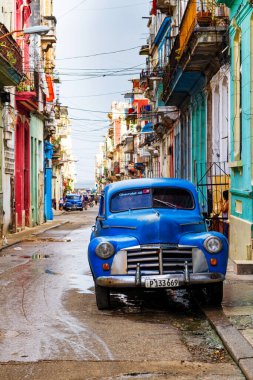 HAVANA, CUBA - 14 Kasım 2017: İnsanlar, eski arabalar ve renkli binaların olduğu tipik sokak sahnesi. 2 milyondan fazla nüfusuyla Havana, Küba 'nın başkenti ve Karayipler' in en büyük şehridir.