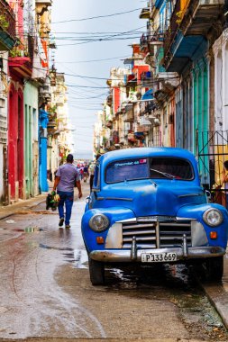 HAVANA, CUBA - 14 Kasım 2017: İnsanlar, eski arabalar ve renkli binaların olduğu tipik sokak sahnesi. 2 milyondan fazla nüfusuyla Havana, Küba 'nın başkenti ve Karayipler' in en büyük şehridir.