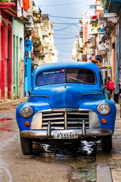HAVANA, CUBA - 14 Kasım 2017: İnsanlar, eski arabalar ve renkli binaların olduğu tipik sokak sahnesi. 2 milyondan fazla nüfusuyla Havana, Küba 'nın başkenti ve Karayipler' in en büyük şehridir.