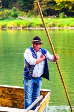 SZCZAWNICA, POLAND - OCT 7, 2018: Tipik Polonyalı sanatçılar nehirde turist sallıyor. Rafting, Pieniny dağlarında çok popüler bir turistik merkezdir..