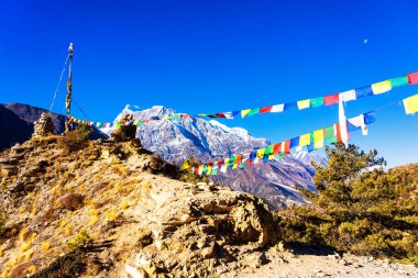 Nepal 'de popüler bir turizm beldesi olan Annapurna Circuit Trail' in panoramik manzarası. Thorong La ya da Thorung La geçidine. Rüzgarda dalgalanan renkli Budist bayraklarıyla.