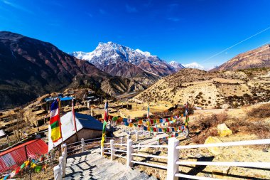 Nepal 'de popüler bir turizm beldesi olan Annapurna Circuit Trail' in panoramik manzarası. Thorong La ya da Thorung La geçidine. Rüzgarda dalgalanan renkli Budist bayraklarıyla.