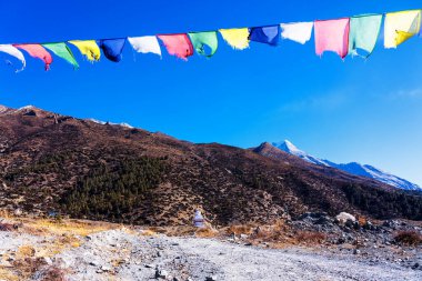 Nepal 'de popüler bir turizm beldesi olan Annapurna Circuit Trail' in panoramik manzarası. Thorong La ya da Thorung La geçidine. Rüzgarda dalgalanan renkli Budist bayraklarıyla.