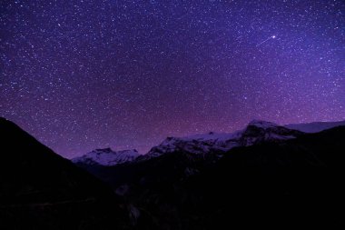 Samanyolu ve dağlar. Himalaya dağları ve yıldızlı gökyüzü ile Nepal 'de inanılmaz bir manzara. Karlı zirveli kayalar ve yıldızlı gökyüzü. Annapurna Dağları. Parlak Samanyolu ile gece manzarası