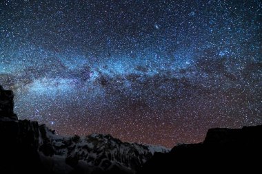 Samanyolu ve dağlar. Himalaya dağları ve yıldızlı gökyüzü ile Nepal 'de inanılmaz bir manzara. Karlı zirveli kayalar ve yıldızlı gökyüzü. Annapurna Dağları. Parlak Samanyolu ile gece manzarası