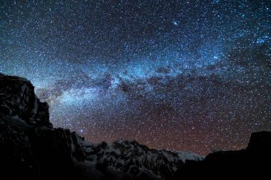 Samanyolu ve dağlar. Himalaya dağları ve yıldızlı gökyüzü ile Nepal 'de inanılmaz bir manzara. Karlı zirveli kayalar ve yıldızlı gökyüzü. Annapurna Dağları. Parlak Samanyolu ile gece manzarası