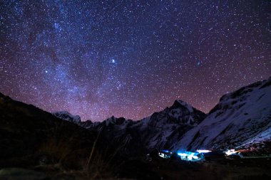 Samanyolu ve dağlar. Himalaya dağları ve yıldızlı gökyüzü ile Nepal 'de inanılmaz bir manzara. Karlı zirveli kayalar ve yıldızlı gökyüzü. Annapurna Dağları. Parlak Samanyolu ile gece manzarası