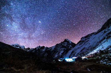 Samanyolu ve dağlar. Himalaya dağları ve yıldızlı gökyüzü ile Nepal 'de inanılmaz bir manzara. Karlı zirveli kayalar ve yıldızlı gökyüzü. Annapurna Dağları. Parlak Samanyolu ile gece manzarası