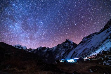Samanyolu ve dağlar. Himalaya dağları ve yıldızlı gökyüzü ile Nepal 'de inanılmaz bir manzara. Karlı zirveli kayalar ve yıldızlı gökyüzü. Annapurna Dağları. Parlak Samanyolu ile gece manzarası