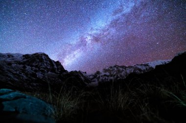 Samanyolu ve dağlar. Himalaya dağları ve yıldızlı gökyüzü ile Nepal 'de inanılmaz bir manzara. Karlı zirveli kayalar ve yıldızlı gökyüzü. Annapurna Dağları. Parlak Samanyolu ile gece manzarası