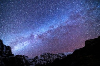Samanyolu ve dağlar. Himalaya dağları ve yıldızlı gökyüzü ile Nepal 'de inanılmaz bir manzara. Karlı zirveli kayalar ve yıldızlı gökyüzü. Annapurna Dağları. Parlak Samanyolu ile gece manzarası