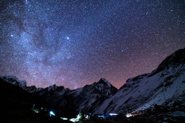 Samanyolu ve dağlar. Himalaya dağları ve yıldızlı gökyüzü ile Nepal 'de inanılmaz bir manzara. Karlı zirveli kayalar ve yıldızlı gökyüzü. Annapurna Dağları. Parlak Samanyolu ile gece manzarası