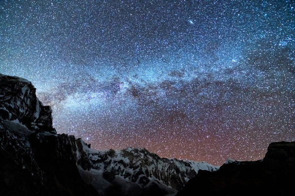 Milky Way and mountains. Amazing scene with Himalayan mountains and starry sky at night in Nepal. Rocks with snowy peak and sky with stars. Annapurna Range. Night landscape with bright milky way