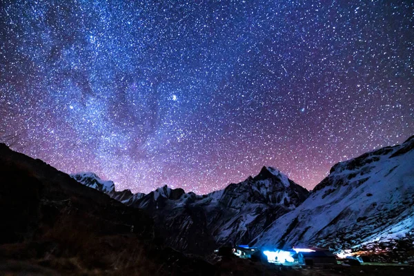 Samanyolu ve dağlar. Himalaya dağları ve yıldızlı gökyüzü ile Nepal 'de inanılmaz bir manzara. Karlı zirveli kayalar ve yıldızlı gökyüzü. Annapurna Dağları. Parlak Samanyolu ile gece manzarası