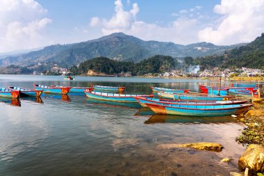 Güzel Phewa gölünün kıyısındaki renkli tekneler. Pokhara, Nepal 'de Annapurna aralığı