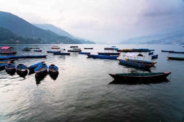Güzel Phewa gölünün kıyısındaki renkli tekneler. Pokhara, Nepal 'de Annapurna aralığı