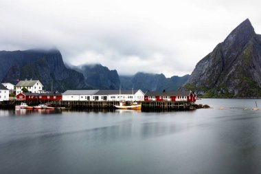 Norveç 'in Lofoten Adaları' ndaki kırmızı ve sarı rorbu evleriyle ünlü bir turistik bölge olan Hamnoy balıkçı köyü. Sakin, bulanık su