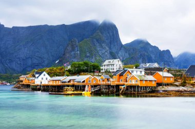 Norveç 'in Lofoten Adaları' ndaki kırmızı ve sarı rorbu evleriyle ünlü bir turistik bölge olan Hamnoy balıkçı köyü. Sakin, bulanık su