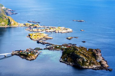 Göz kamaştırıcı dağların güneşli panoramik manzarası ve Reinebringen tepesinden Norveç 'in Lofoten adalarındaki Reine köyü. Gökkuşağı ve engebeli tepeleri olan manzaralı bir manzara.