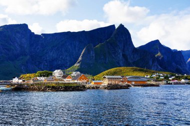 Norveç 'in Lofoten Adaları' ndaki kırmızı ve sarı rorbu evleriyle ünlü bir turistik bölge olan Hamnoy balıkçı köyü. Sakin, bulanık su
