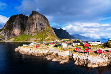 Norveç 'in Lofoten Adaları' ndaki kırmızı ve sarı rorbu evleriyle ünlü bir turistik bölge olan Hamnoy balıkçı köyü. Sakin, bulanık su