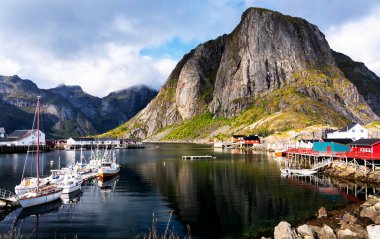 Norveç 'in Lofoten Adaları' ndaki kırmızı ve sarı rorbu evleriyle ünlü bir turistik bölge olan Hamnoy balıkçı köyü. Sakin, bulanık su